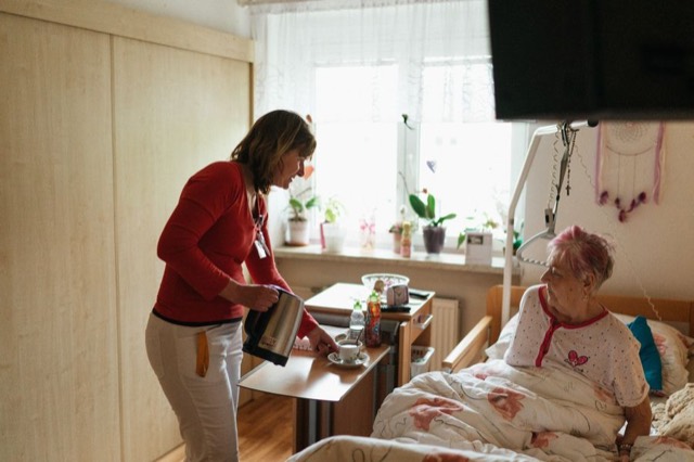 Pflegekraft bringt einer Seniorin Tee